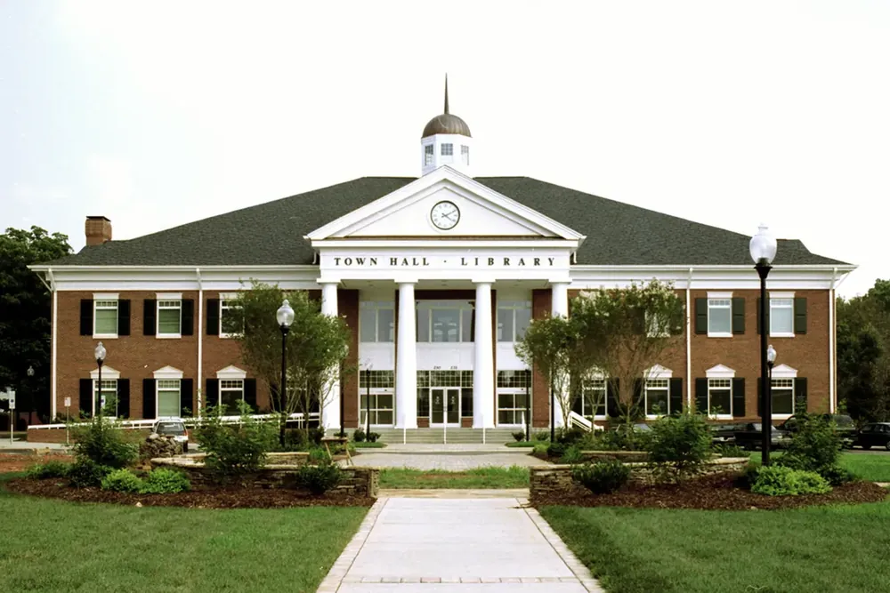 The white-columned Matthews Town Hall and library building behind a lawn in North Carolina