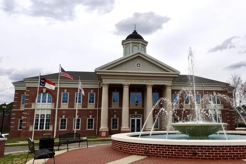 The columned brick Mint Hill Town Hall behind a splashing fountain in North Carolina
