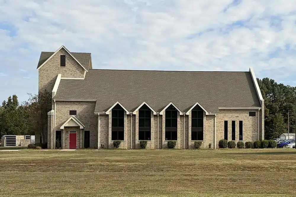 The tan brick All Saints Anglican Church across a wide lawn in Weddington, North Carolina